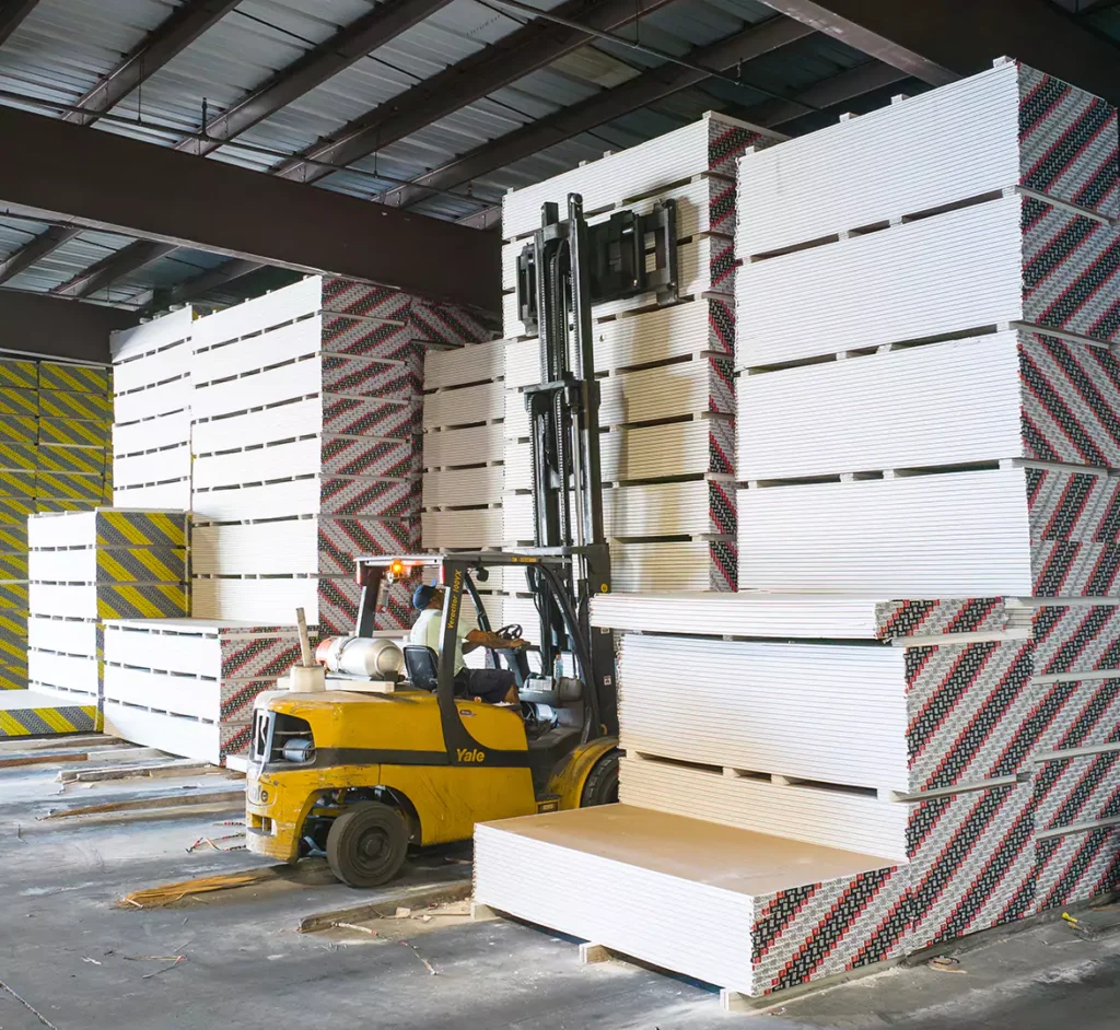 Forklift moving stacked drywall sheets in the covered warehouse at Colonial Building Supply