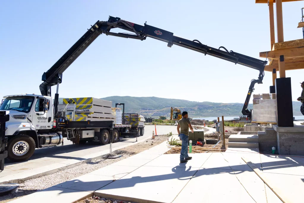 Colonial boom truck lifting drywall to the upper floor of a Utah jobsite